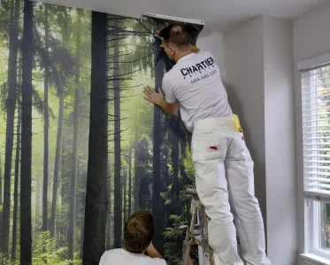 Two men collaboratively painting a mural on a wall.