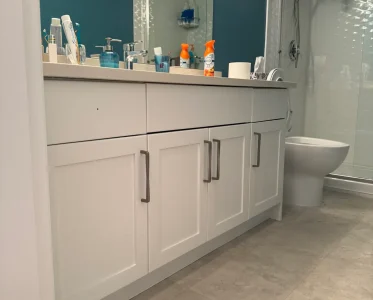 Bathroom vanity with toiletries and personal care items on a white countertop.