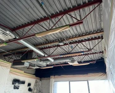 Large industrial building under construction with exposed pipes and wires.