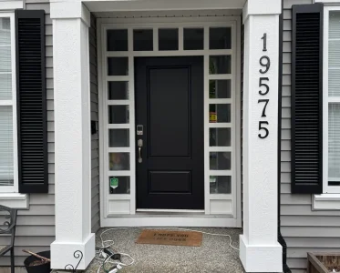 Open black front door with white frame, revealing interior of a house.
