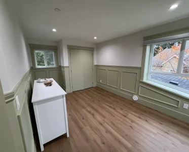 Empty green kitchen with hardwood floor, sink, and refrigerator.