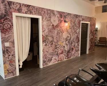 A salon with a floral patterned wall and multiple chairs for customers.