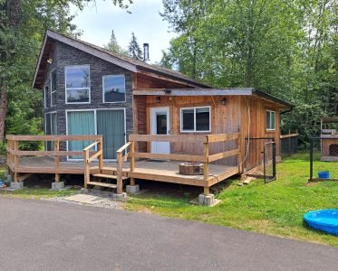 Cozy wooden house with deck and porch surrounded by trees.